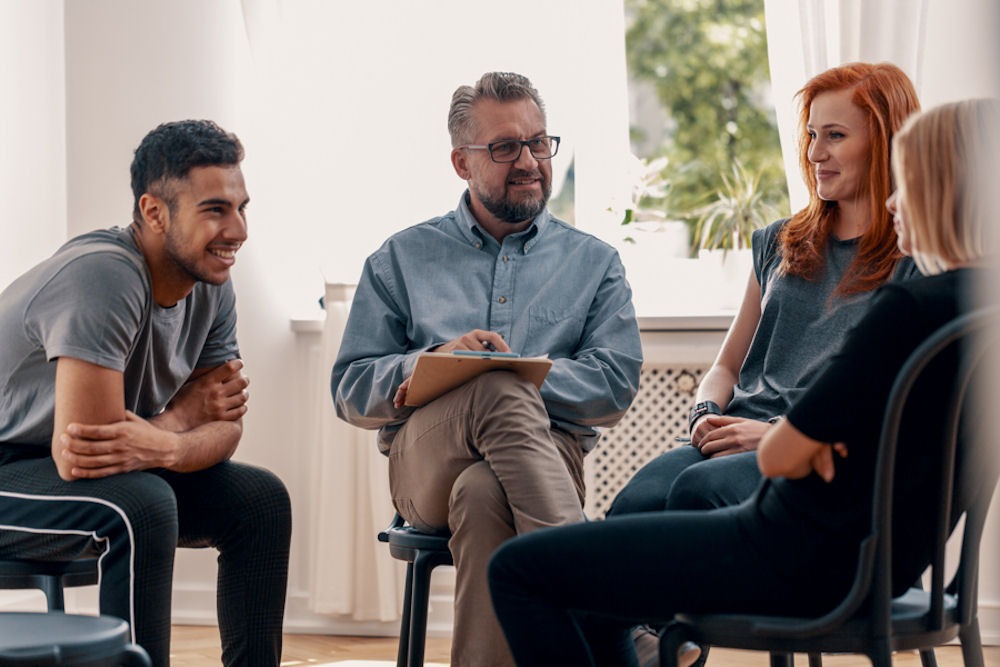 group of young adults sitting in a circle for therapy