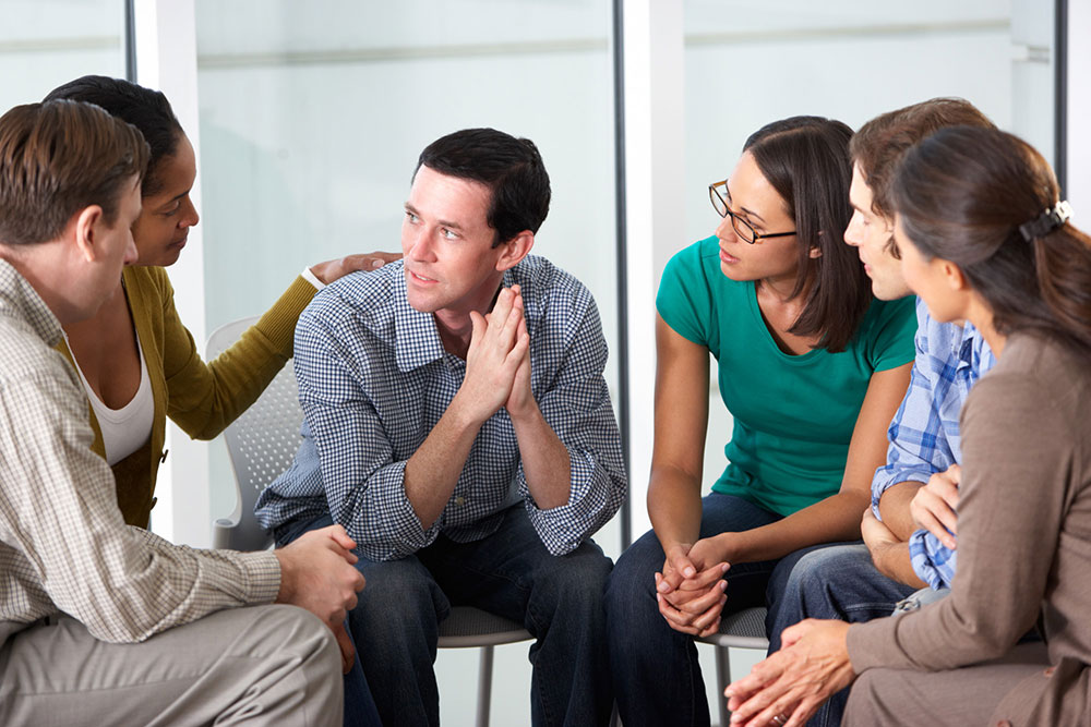 man receiivng support in group therapy