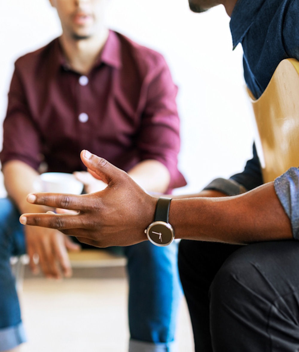 a man's hand as he sits in group therapy