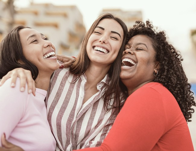 three women holding each other and laughing