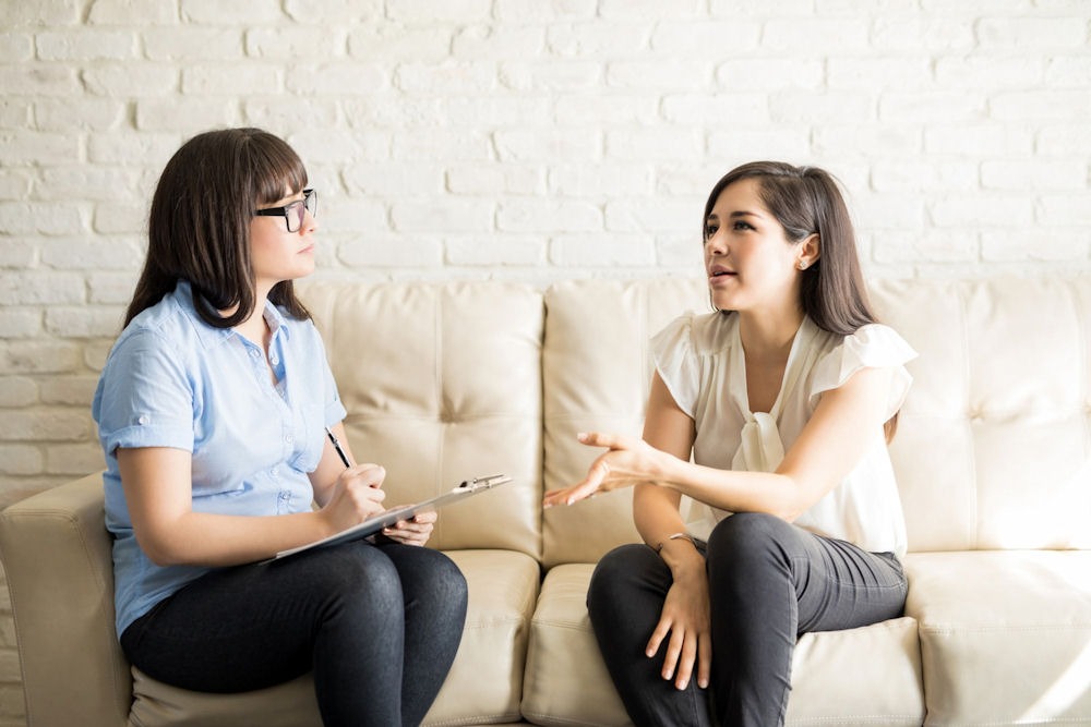 therapist and her patient sitting on couch having a discussion