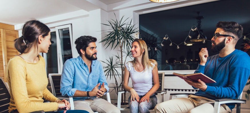 four adults sitting in chairs having a discussion