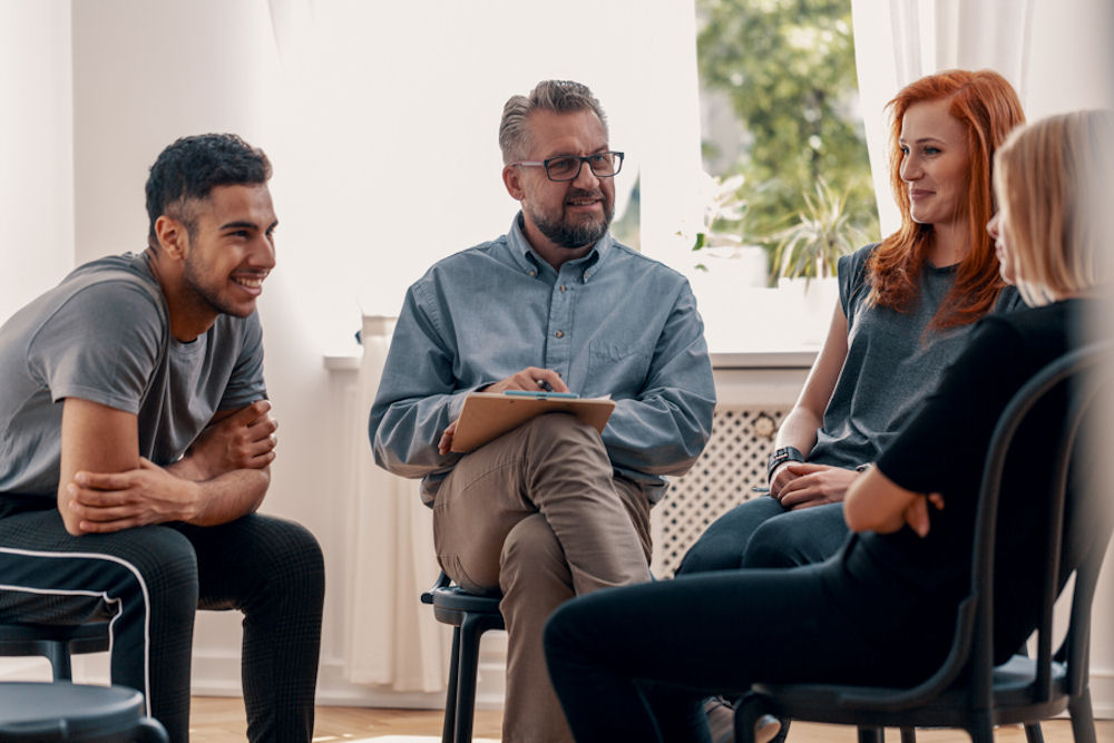 group of adults sitting in chairs in therapy session