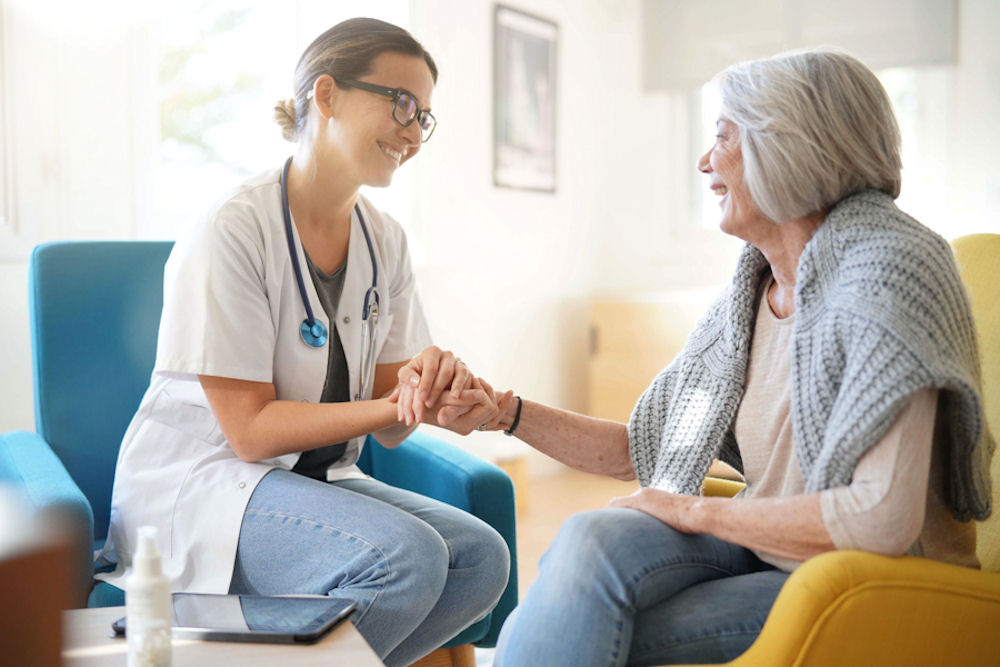 doctor holding an elderly patients hand while they sit together